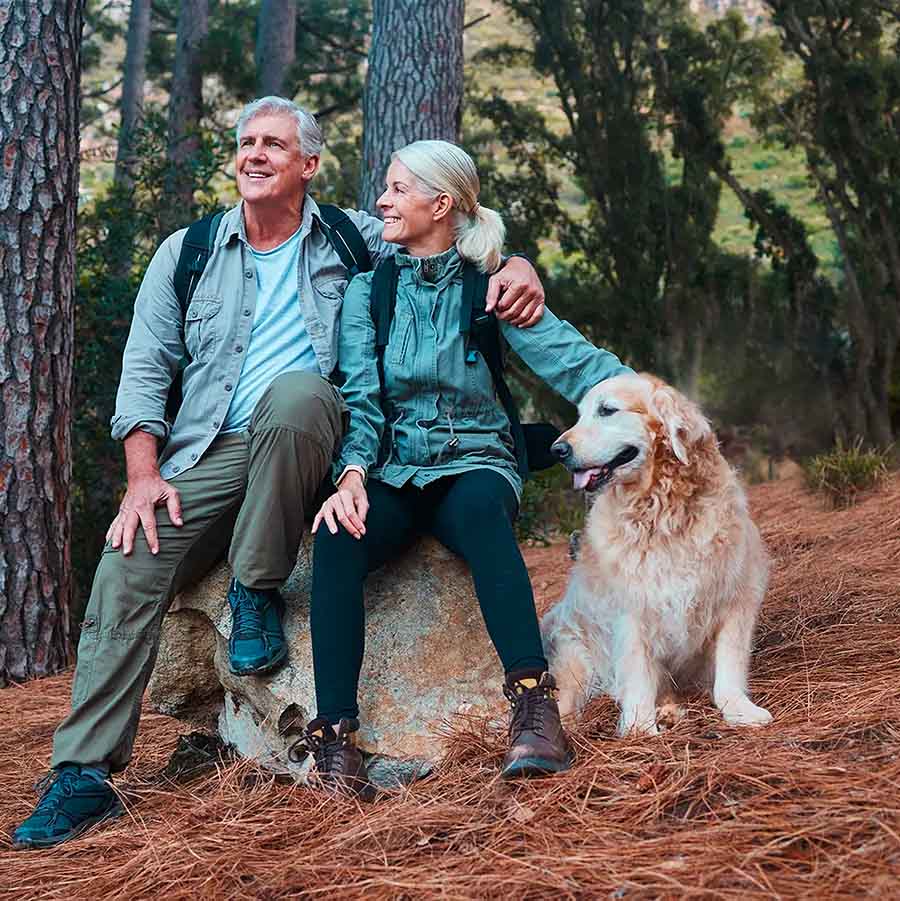 Couple de personnes âgées faisant de la randonnée avec leur chien en forêt ostéopathe nyon